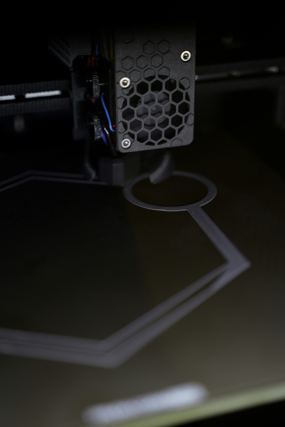 Buse d'une imprimante 3D en train de tracer les premières couches d'une pièce